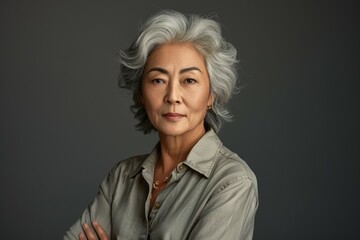 A woman with gray hair and a necklace is posing for a picture