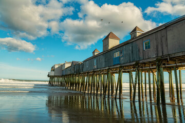 old wooden pier and pier with cafes in the water on the ocean shore on a sunny day and fluffy clouds. rough sea with waves. Old Orchard Beach. USA. Maine