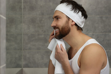 Washing face. Man with headband and towel in bathroom, space for text