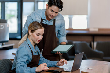 Partnership of cafe barista, entrepreneur and small business owners planning budget. brainstorming coffee shop innovation strategy on laptop, taking notes. Startup entrepreneurs small business meeting