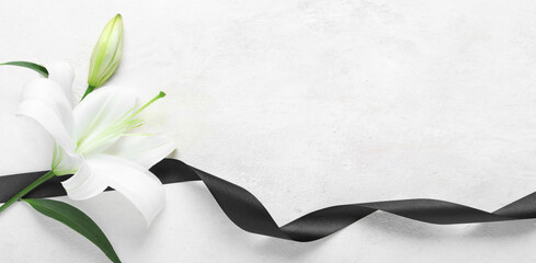 Beautiful lily flowers with funeral ribbon on white background