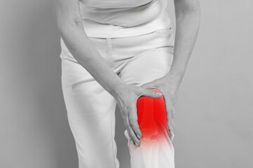 Arthritis symptoms. Woman suffering from pain in her knee on background, closeup. Black and white effect with red accent in painful area © New Africa