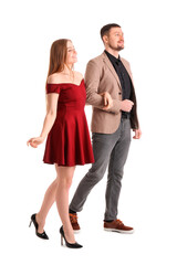 Elegant young couple walking hand in hand on white background