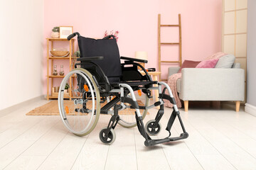 Modern empty wheelchair in living room near color wall