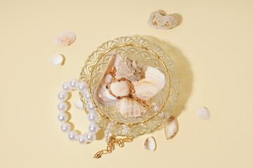 Cup with different beautiful bracelets and seashells on beige background