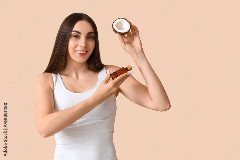 Canvas Prints Beautiful young woman with coconut and dropper bottle on beige background