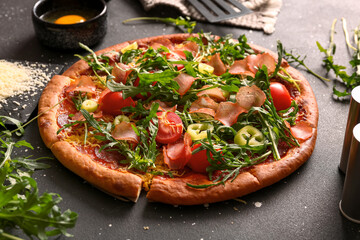 Delicious pizza with tomatoes and arugula on black background