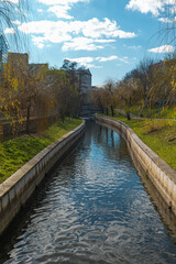 Detail of Pavia River in Viseu, Portugal, with water, green trees and a blue sky with clouds - obrazy, fototapety, plakaty