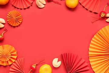 Frame made of fortune cookies with mandarins and Chinese symbols on red background. New Year...
