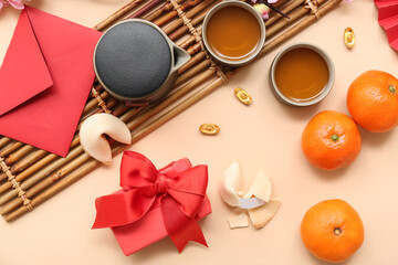 Obraz na płótnie Canvas Gift box with fortune cookies, mandarins and cups of tea on beige background. New Year celebration