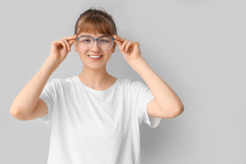 Young woman in eyeglasses on light background. Glaucoma awareness month