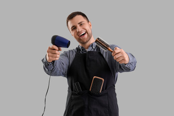 Naklejka premium Male hairdresser with dryer and brush on light background