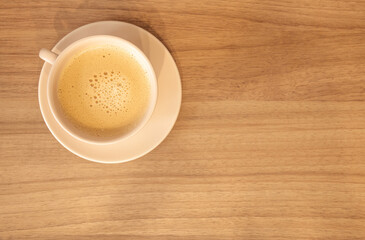 Xícara de café com leite, cor clara, bege,  madeira, pires, espaço negativo para escrita à...