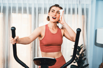Athletic and sporty woman running on elliptical running machine during home body workout exercise...