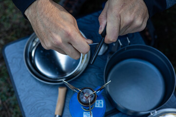 Top-Down View of Hands Lighting Camping Stove with Flint