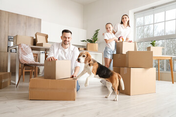 Happy family with Beagle dog packing boxes in kitchen on moving day