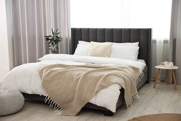 Fototapeta na wymiar Soft beige plaid on bed in stylish bedroom. Interior design