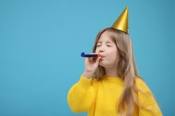 Cute little girl in party hat with blower on light blue background. Space for text