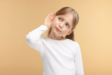 Little girl with hearing problem on pale brown background