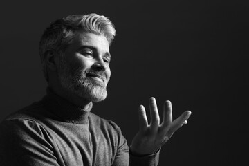 Portrait of handsome man gesturing on dark background. Black and white effect