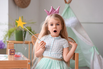Shocked little girl dressed as fairy sitting at home