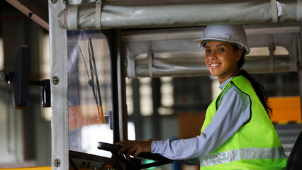 Female logistics warehouse staff wearing green safety vests test-driving a prototype of machinery on a rail track in the factory.