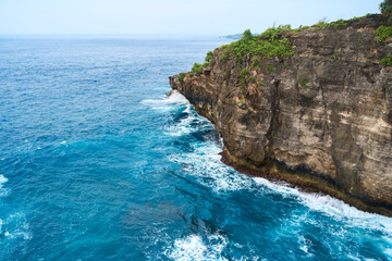 Cinematic aerial landscape shots of the beautiful island of Nusa Penida. Huge cliffs by the shoreline and hidden dream beaches with clear water and foaming wave.