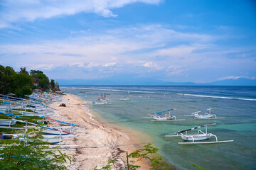Traditional local colored fisherman's catamaran boats are lined up on the ocean shore on an island in Indonesia.