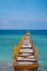 The old wooden pier goes into the horizon of the incredible azure color of the ocean.