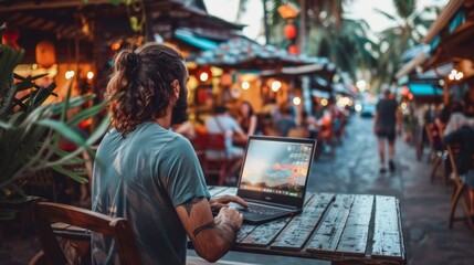 Man Working on Laptop at Tropical Street Cafe During Sunset