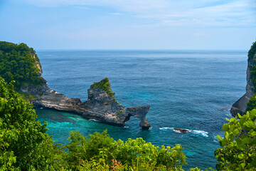 An Arch Rock in the ocean with turquoise blue water on the island of Nusa Penida near the popular Diamond Beach.
