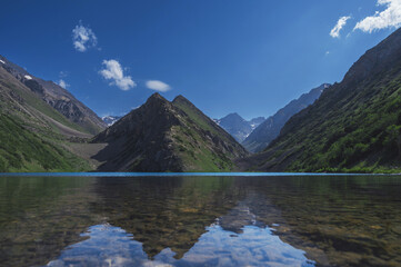 Fototapeta na wymiar Lake with clear blue water in the mountains under the sky with clouds in summer