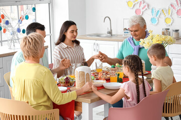 Happy family praying before Easter dinner in kitchen