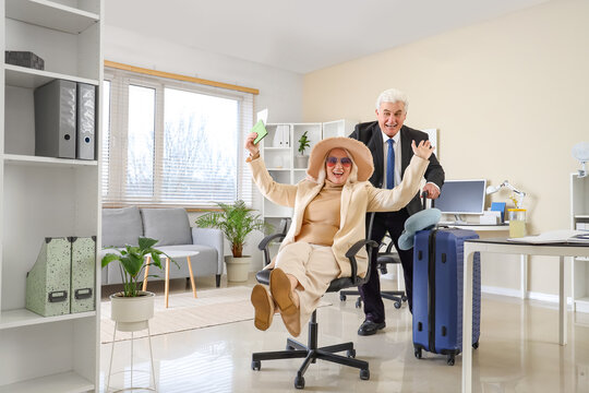 Mature business people with passport and suitcase ready for summer vacation in office