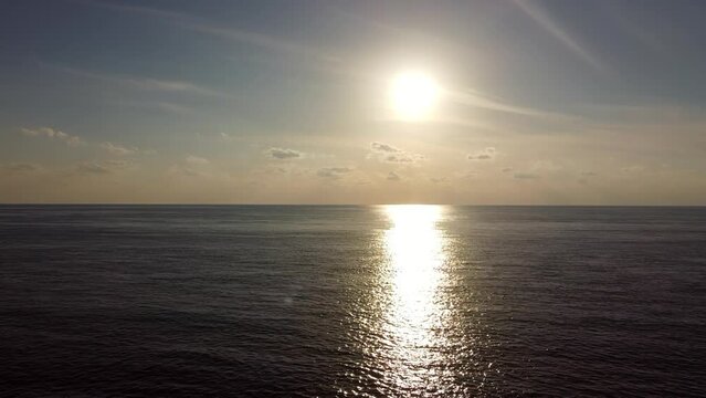 Shot of the sea with the sun directly above it, casting sunlight reflections on the water.
