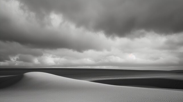 a black and white photo of a vast expanse of sand dunes under a cloudy sky with a sun in the distance.