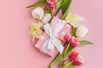 Obraz na płótnie Canvas Gift box with beautiful tulips and daffodil flowers on pink background
