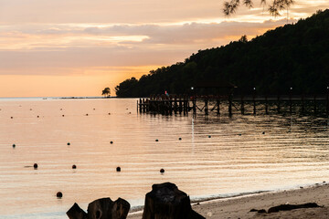 Puesta de sol en playa paradisíaca de Borneo con embarcadero de madera