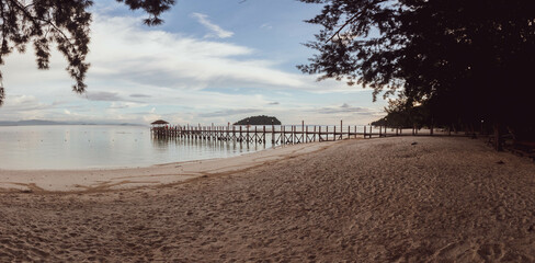 Puesta de sol en playa paradisíaca de Borneo, con embarcadero de madera