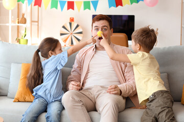 Little children pranking their father with clown nose and face paintings at home. April Fool's Day prank - obrazy, fototapety, plakaty