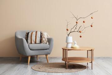Vase with tree branches and Easter eggs on table in interior of living room