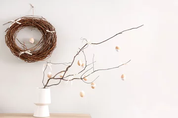 Foto op Canvas Vase with tree branches, Easter eggs and bows on table near light wall in room © Pixel-Shot
