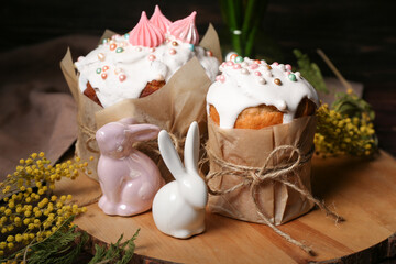 Easter cakes, rabbits and mimosa on wooden tray, closeup