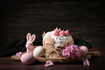 Easter cake, painted eggs, hyacinth and wooden tray on wooden background