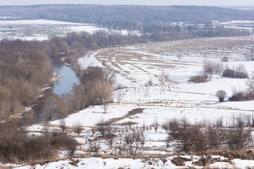 A bend in the river and a snow-covered field - 769140815