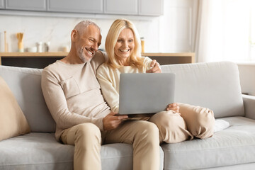 Senior couple laughing while using a laptop