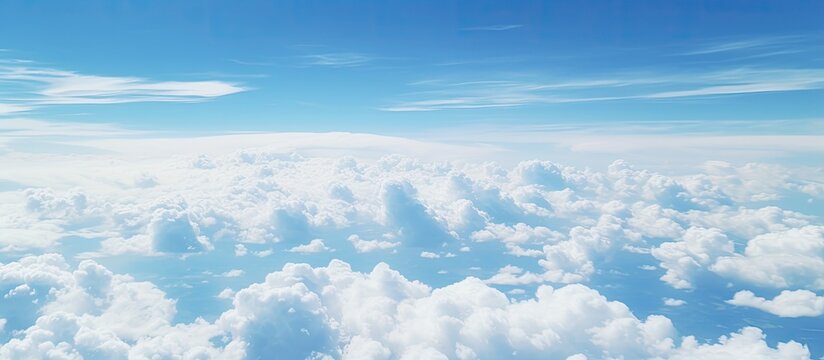 The image presents a picturesque sight of a clear blue sky with fluffy white clouds as seen from high up in an airplane