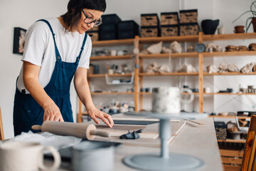 A crafty potter manipulating wet clay at pottery workshop.