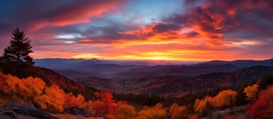 The sun setting over a serene autumn landscape, showcasing the mountains, trees, and colorful foliage