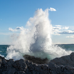 Fototapeta na wymiar Waves crashing at cliff in sunlight. High quality photo
